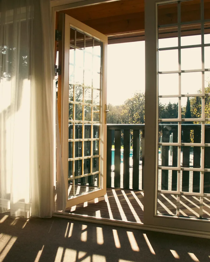 Warm afternoon light coming through open French doors onto a balcony