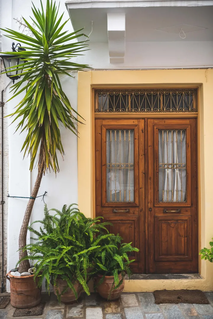 Wooden front doors framed by green plants