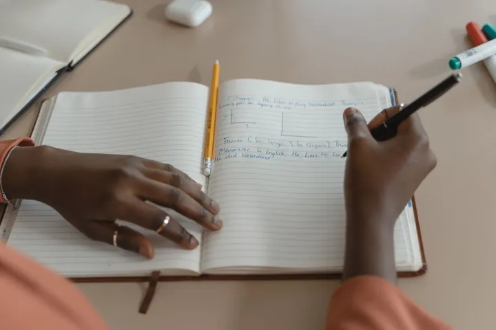 Hands writing notes in an open notebook